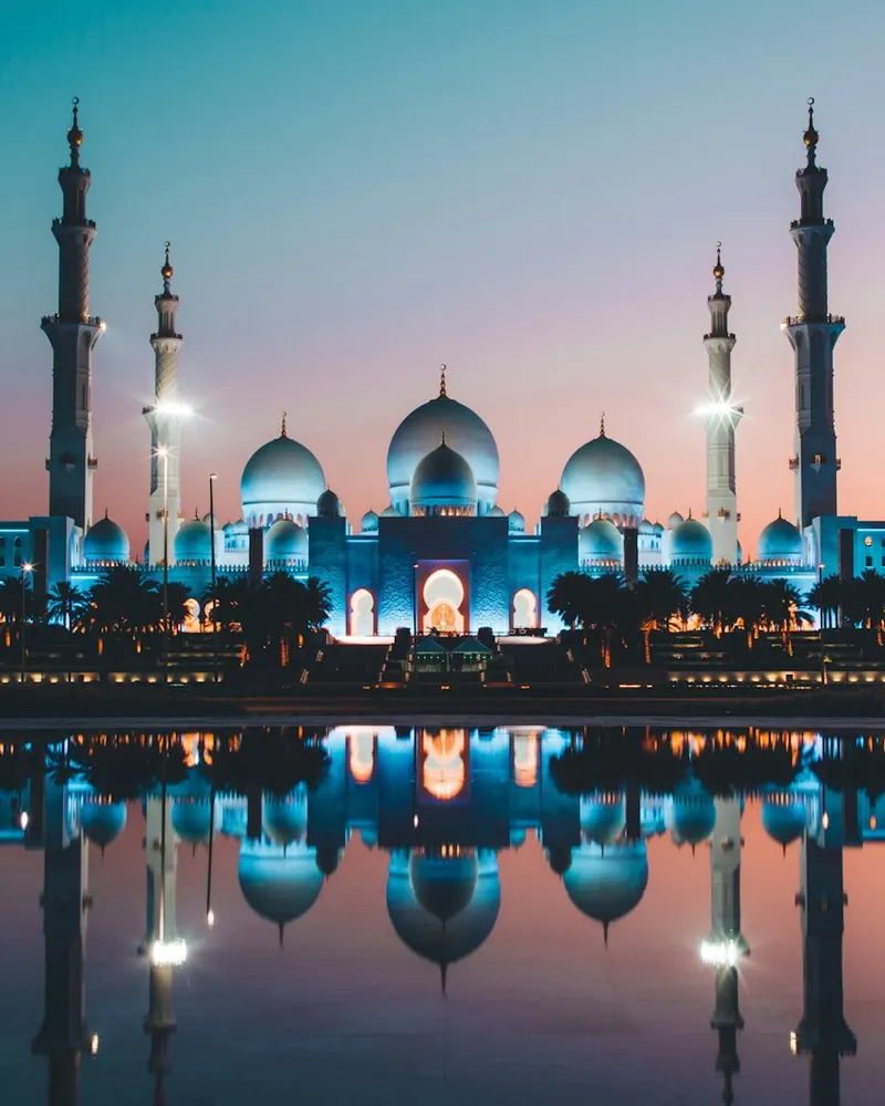 The Sheikh Zayed Grand Mosque reflected in a pool at low sun in Abu Dhabi