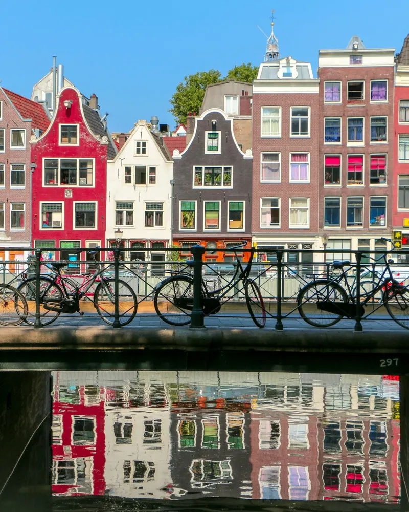 Bicycles parked on a bridge over a canal in Amsterdam with historic buildings