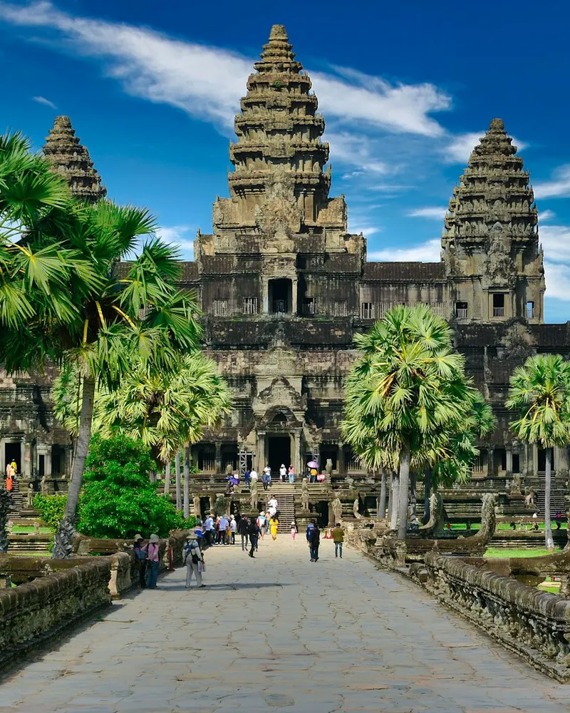 People walking along a stone path toward the Angkor Wat temple in Cambodia