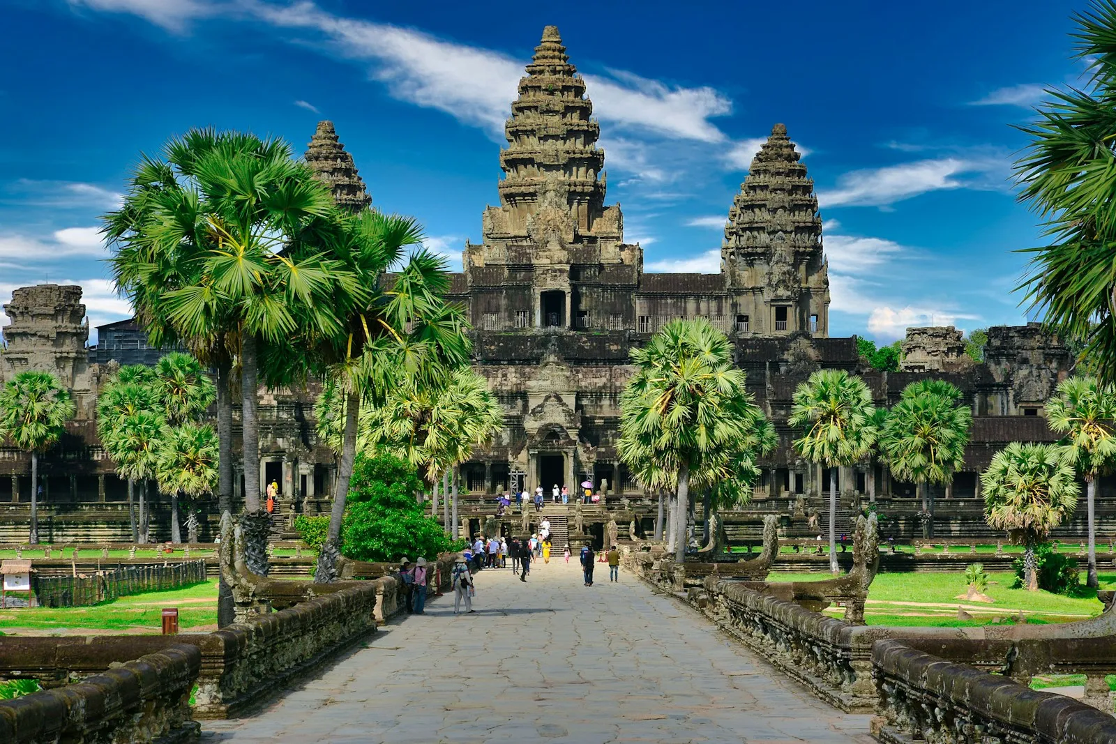 People walking along a stone path toward the Angkor Wat temple in Cambodia