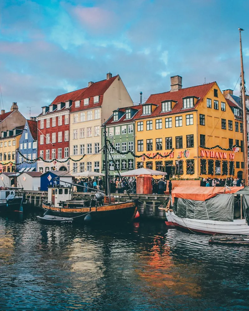 Boats moored along the canal in front of colorful buildings in Nyhavn, Copenhagen