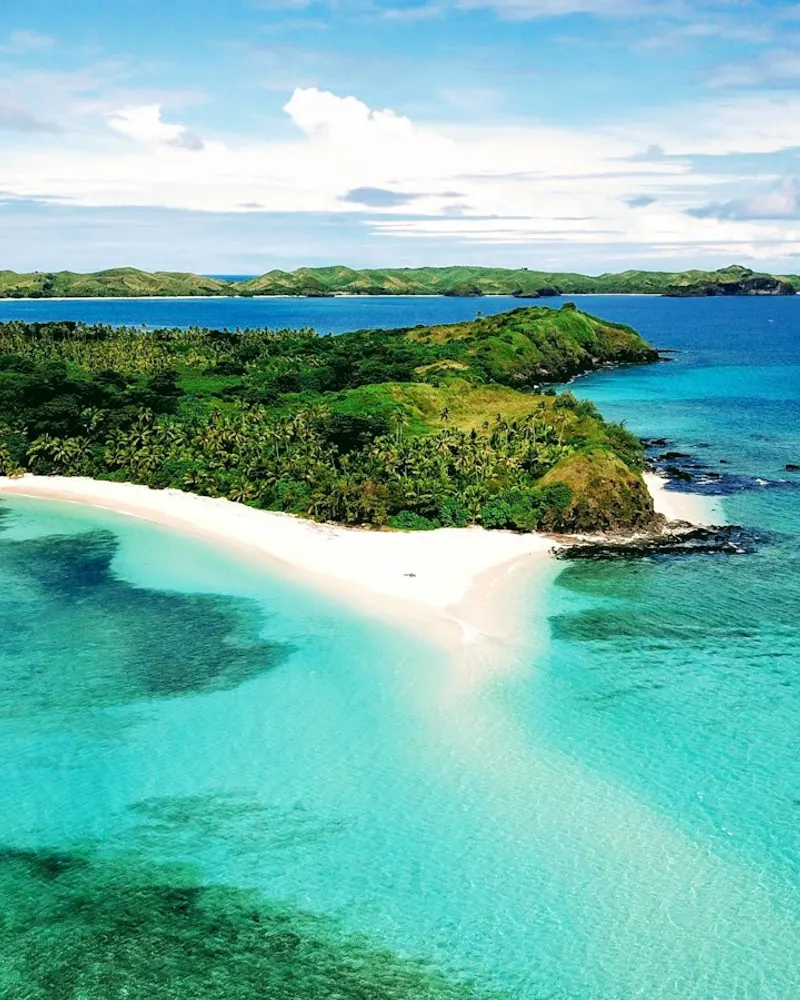 a beach with blue water and green land