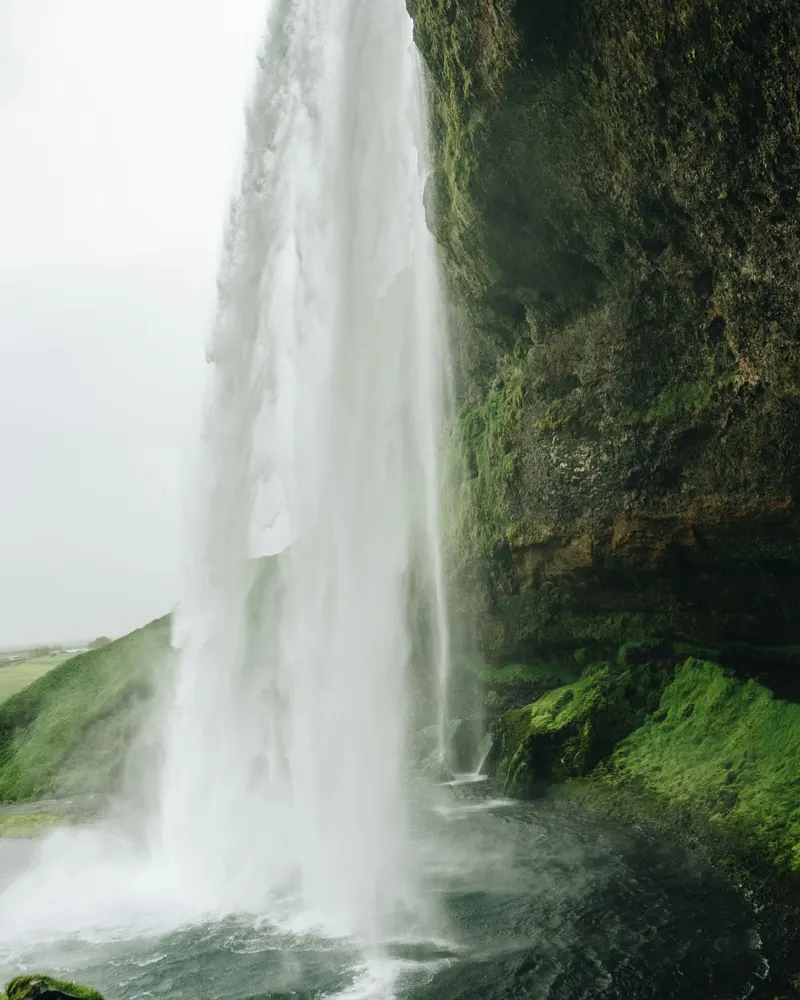 Waterfall descending over green cliffs in Iceland