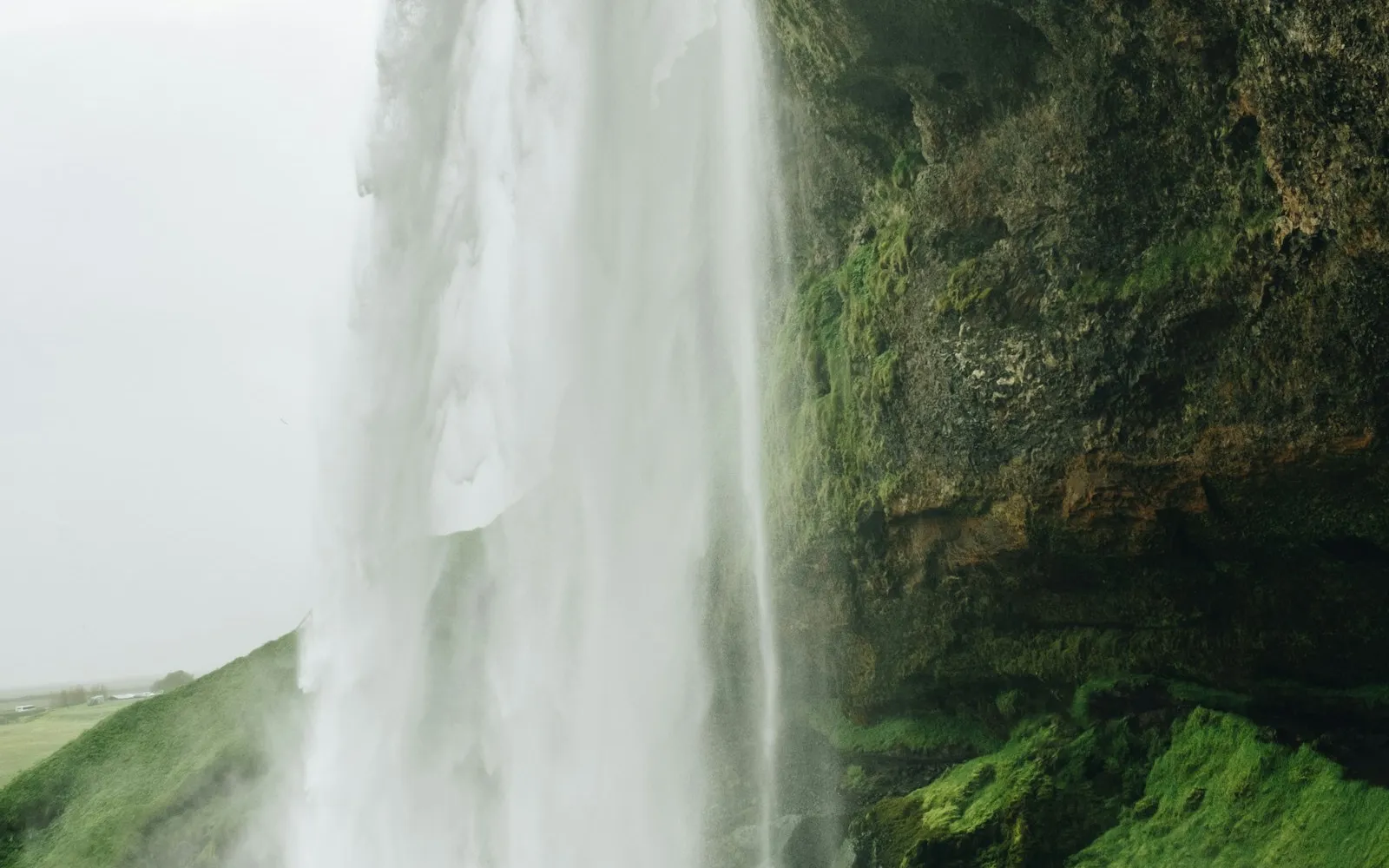 Waterfall descending over green cliffs in Iceland