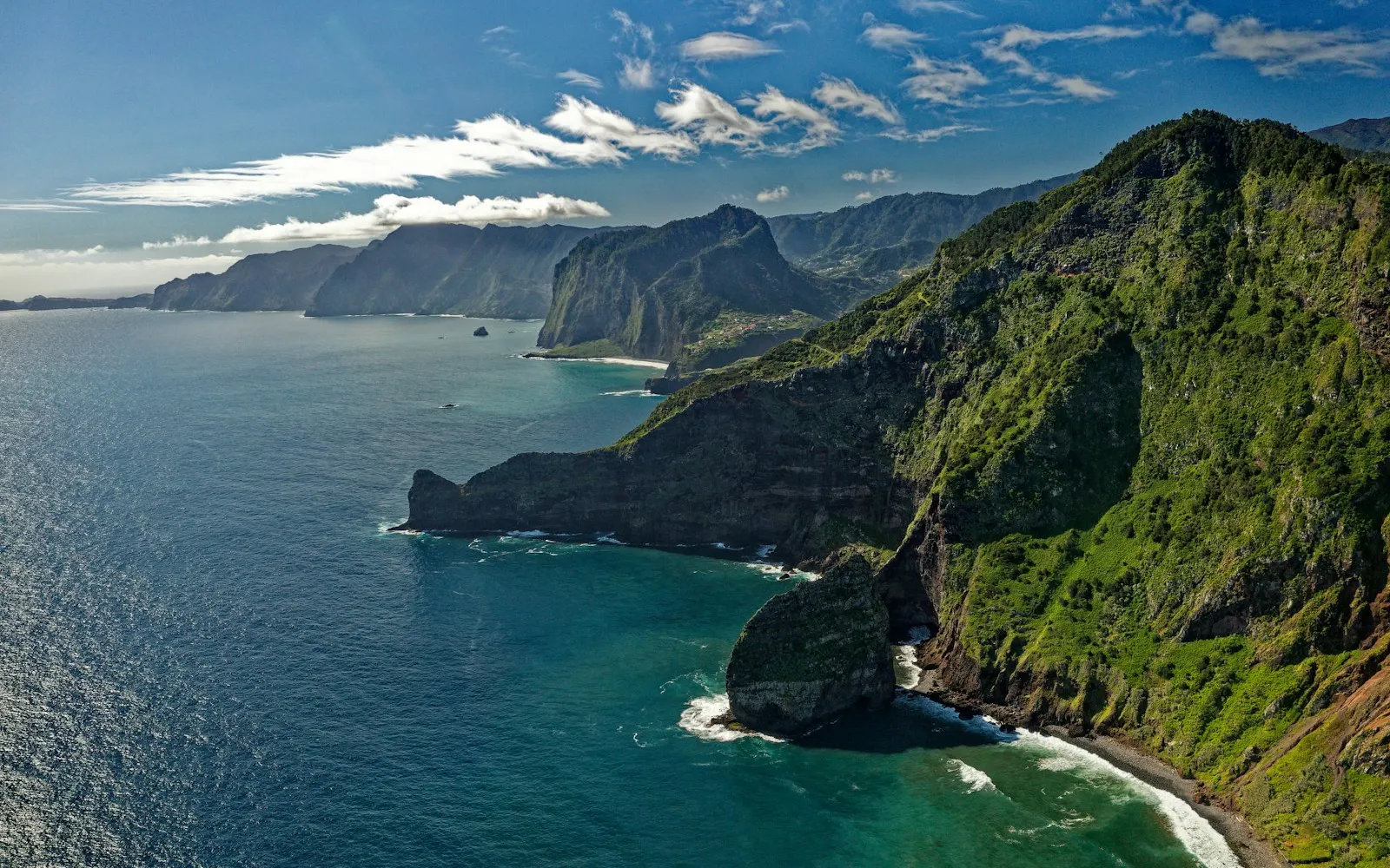 green and brown mountain beside body of water during daytime