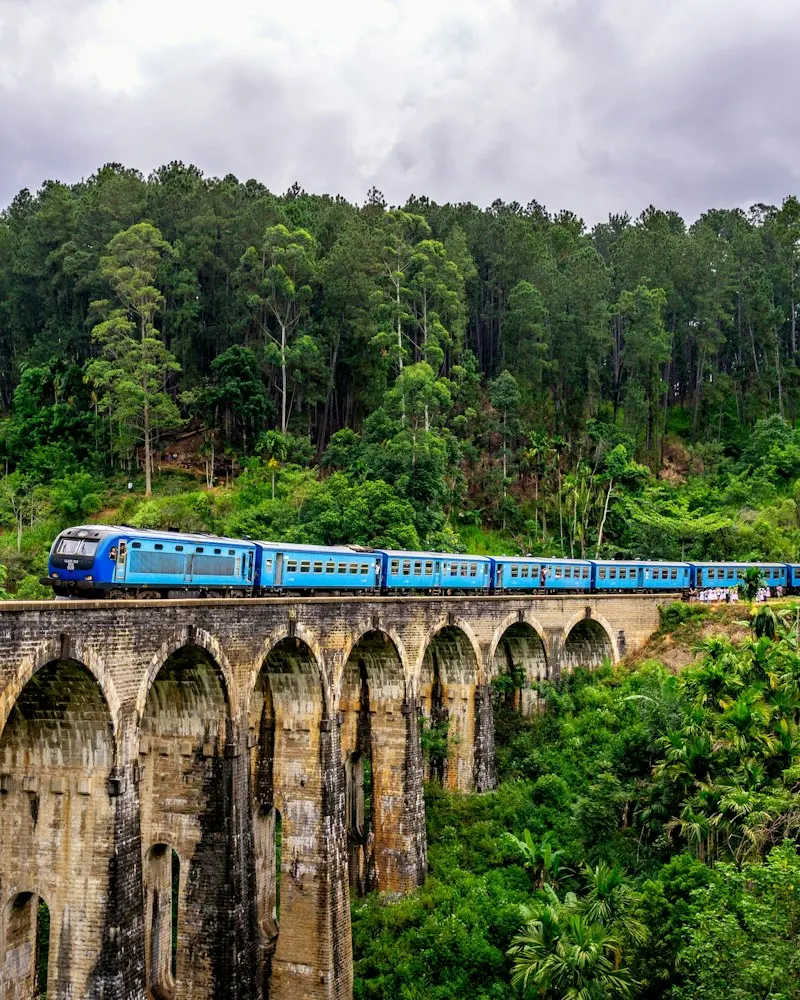 A blue train crossing the Nine Arches Bridge in Ella, Sri Lanka