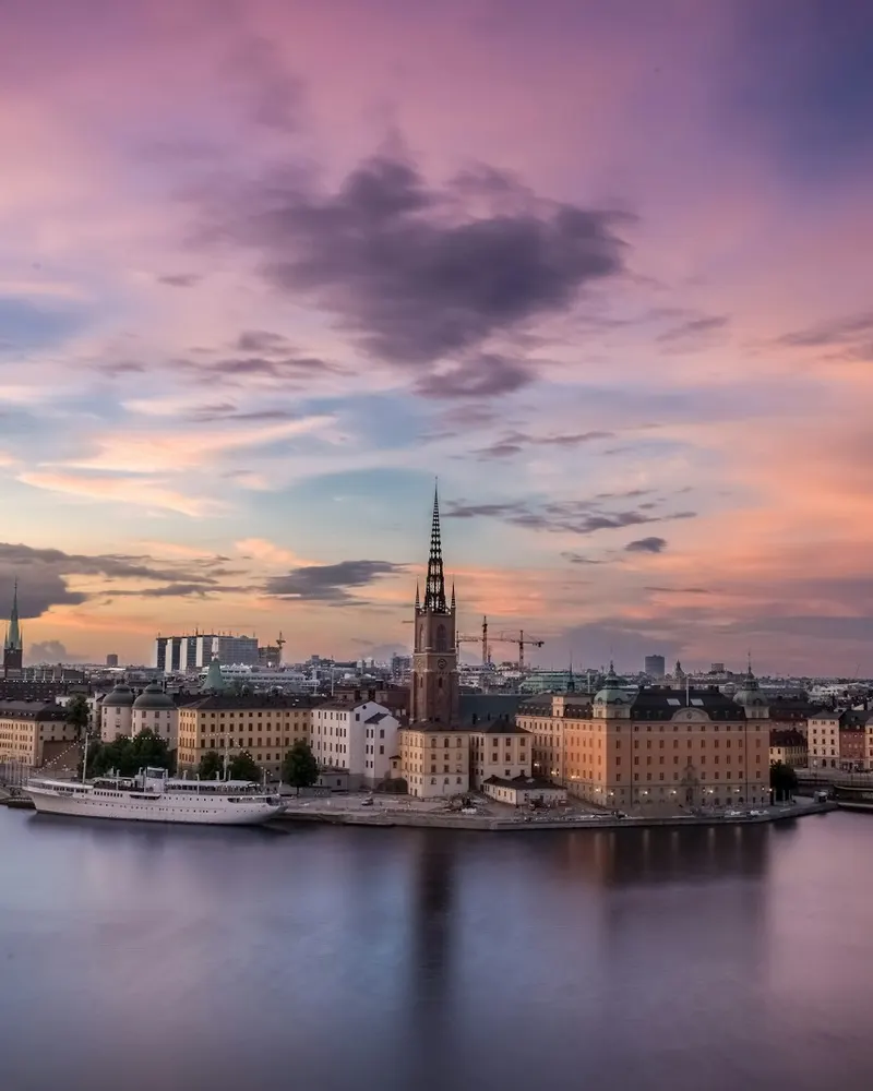 The Riddarholmen Church spire rising above the Stockholm waterfront under a purple sky