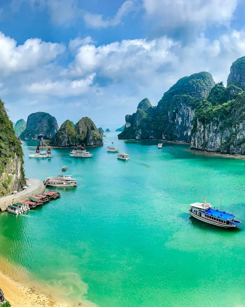 Boats on the turquoise water of Ha Long Bay surrounded by limestone karst islands